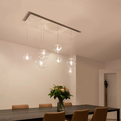 Novi 7 hanglamp met witte plafondplaat en zeven glazen bollen.